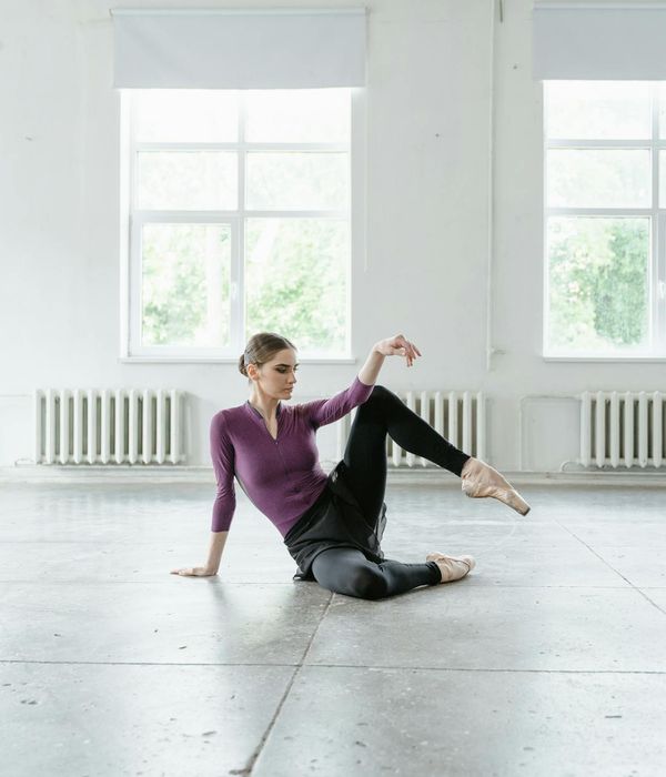 Woman performing a gentle stretching pose in a bright studio.